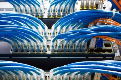 Rows of AI data center switches with dense fiber-optic cabling forming the back-end network fabric of a GPU cluster